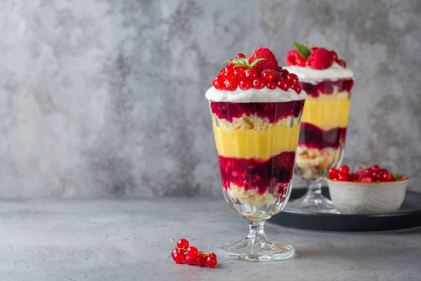 Individual size Trifles, layered dessert in glass with berry jelly, custard,  sponge and whipped cream, decorated with fresh berries. Copy space. Individual size Trifles, layered dessert in glass with berry jelly, custard,  sponge and whipped cream, decorated with fresh berries. Copy space. trifle stock pictures, royalty-free photos & images