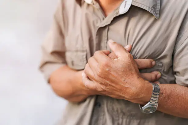 Photo of Close-up of an elderly man's hand held his chest in pain. Concept of heart disease.