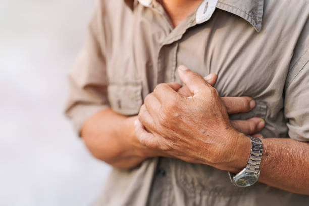 close-up of an elderly man's hand held his chest in pain. concept of heart disease. - chest pain imagens e fotografias de stock