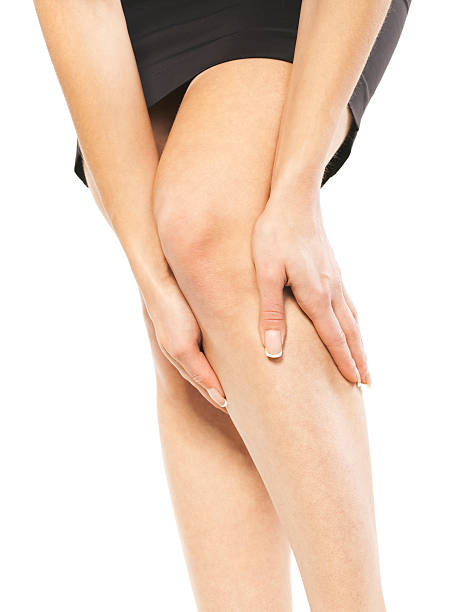 a woman holding her knee in pain - woman legs veins stockfoto's en -beelden