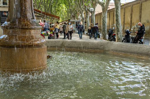 Palma de Mallorca, Spain; april 23 2021: Close-up of the stone fountain in the historic center of Palma de Mallorca with people out of focus in the background
