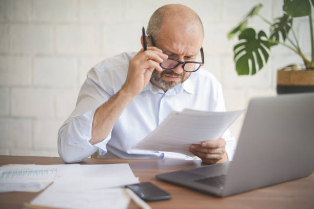 istock mature adult man working from office ( with laptop, paperwork, Negative Emotion) 1338425830