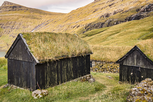 Saksun Village Grass Roof Barns on Faroe Islands. Green grass-covered traditional turf barns, stone huts - traditional faroese thatched roof log cabins. Saksun Village, Saksun Fjord, Northwest Coast of Streymoy Island, Faroe Islands, Kingdom of Denmark, Nordic Countries, Europe