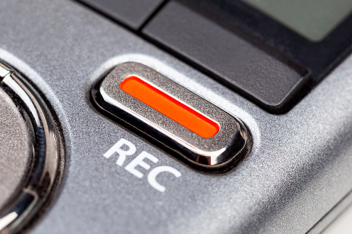 Botón de grabación REC rojo en una grabadora de voz de audio de bolsillo moderna, cambio de objeto macro primer plano extremo Grabación secreta, equipo de periodista o reportero, concepto abstracto simple de grabación de música en vivo photo