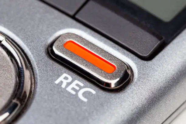 Photo of Red REC recording button on a modern pocket audio voice recorder, switch object macro extreme closeup Secretly recording, journalist or reporter equipment, simple live music recording abstract concept