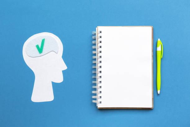 istock A paper silhouette of a thinking human head. Notebook with pen on a blue background. Mock up. Flat lay. Concept of brainstorming and education 1338451000