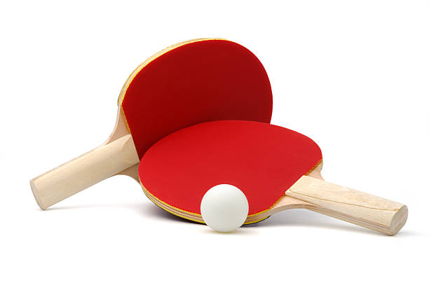 Two red ping-pong paddles and white ball on white ground stock photo