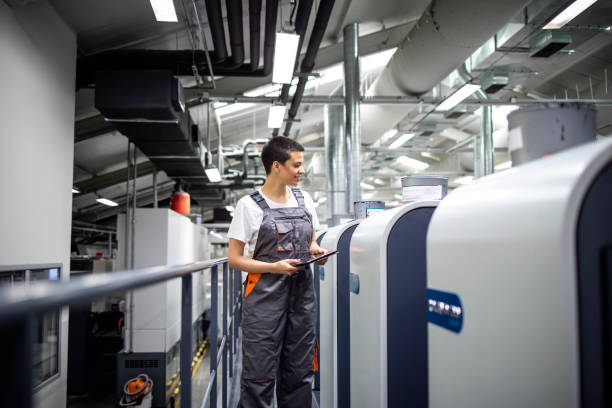 istock Female print worker controlling printing process on modern offset machine in print shop. 1338454117