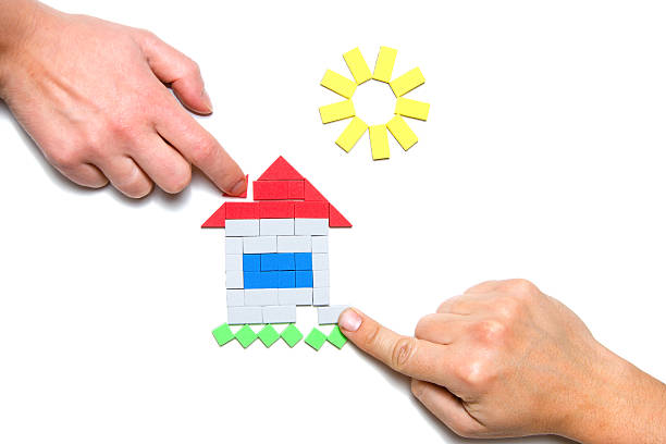 male and female hands building toy house stock photo