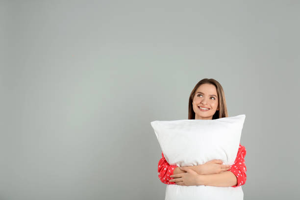 istock Young woman with pillow on grey background. Space for text 1338459910