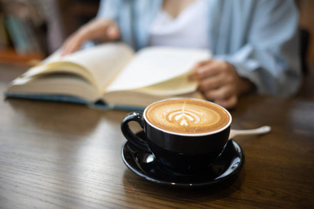 Young woman drinking coffee and reading a book