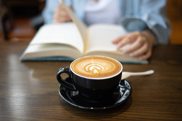 istock Young woman drinking coffee and reading a book 1338459993