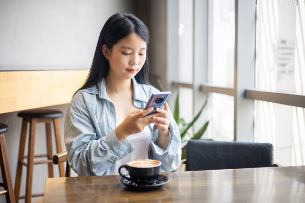 istock Asian young girl using mobile phone in cafe 1338460130