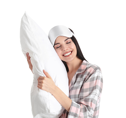 Young woman with pillow and sleep mask on white background