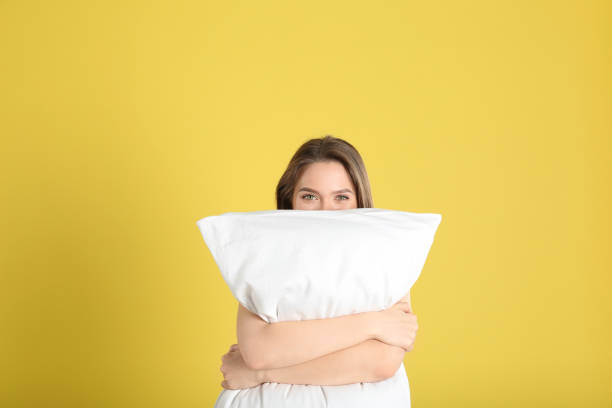 istock Young woman with pillow on yellow background 1338460837