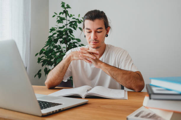 istock Pensive student making notes from laptop. Young man studying at home and prepare for pass exam 1338463114