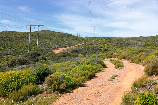 A pylon carrying a high voltage transmission line across rolling hills.