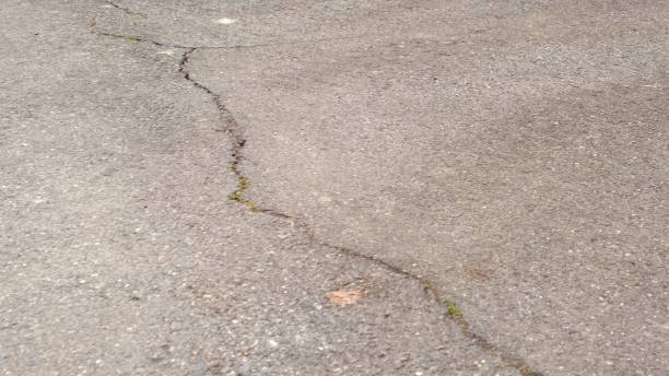 istock Crack on gray asphalt texture background. Road construction and design concept. Worn out bad asphalt 1338467072