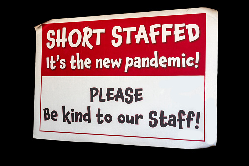 A sign noting a business has a short staff due to the Covid-19 pandemic.