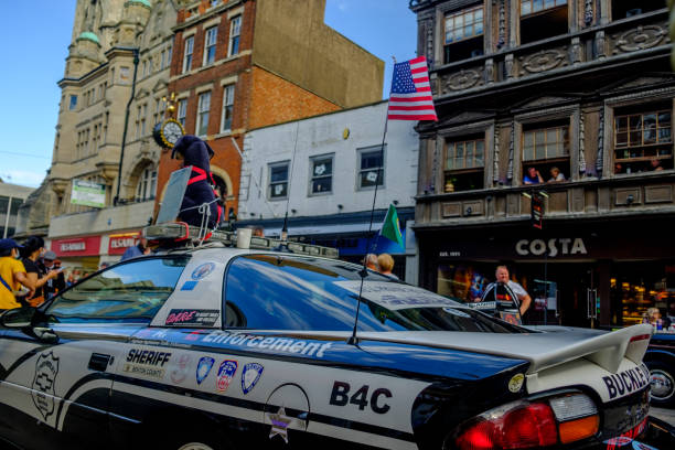 un'auto della polizia americana parcheggiata in una strada con negozi e una caffetteria sullo sfondo a un salone di auto d'epoca nel gloucester gloucestershire nel regno unito che sventola una bandiera degli stati uniti. - 5908 foto e immagini stock