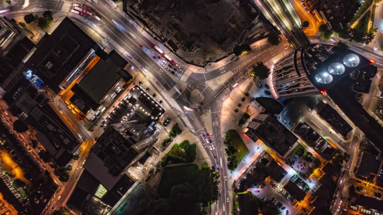 Aerial birds eye overhead top down rising hyperlapse footage of traffic in streets Elephant and Castle district. Busy road intersection at night, long exposure time blurring motion. London, UK