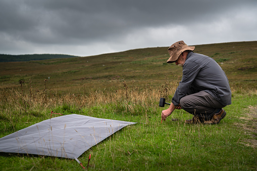 Active retired man making his campsite for wild camping in a remote location in Scotland