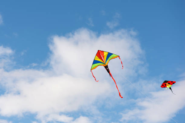 istock Flying kite. A multi-colored kite is flying in the sky. Blue sky with clouds and sun. Space for text or copy space 1338483400