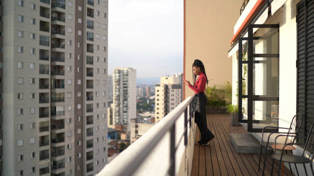 istock Young woman using smartphone on apartment's balcony 1338486485