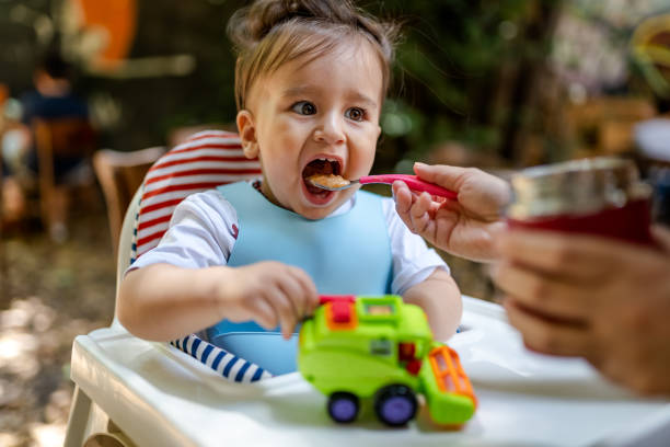 Baby Boy eating homemade soup at outside stock photo