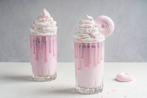 dwie szklanki koktajlu mlecznego jagodowego z bitą śmietaną ozdobioną różową bezą na białym drewnianym tle - cream sprinkles food and drink freshness zdjęcia i obrazy z banku zdjęć