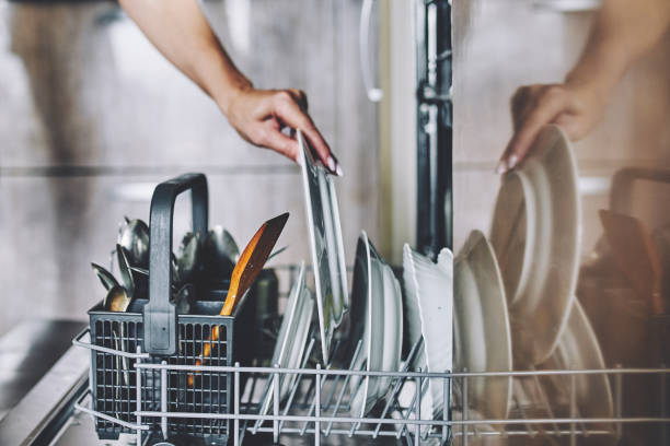 Cleaning dishes in the dishwasher. A woman's hand puts a dirty plate in the dishwasher kitchen dishwasher stock pictures, royalty-free photos & images