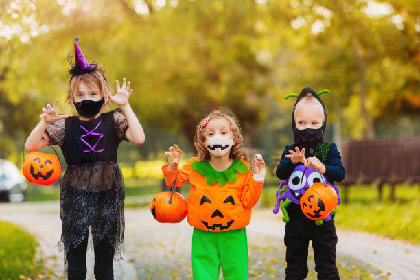 istock Three kid with a basket for sweets making grimaces wearing face mask on Halloween holiday 1338495451