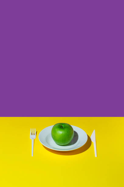 istock Minimal composition with a green apple on a yellow-purple background. Creative concept. 1338495534