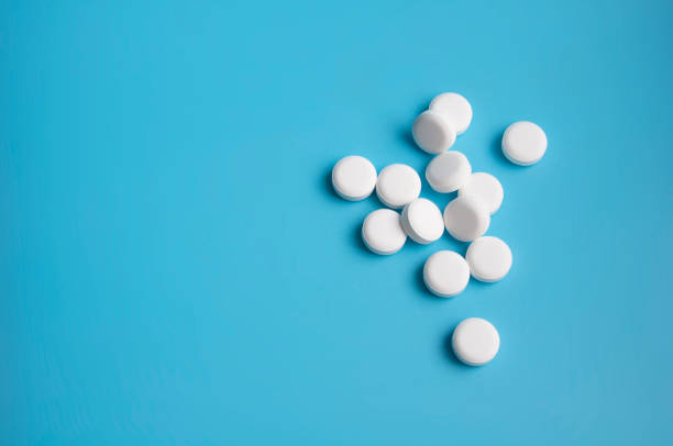 istock whte pills or tablets for virus on blue background 1338499863