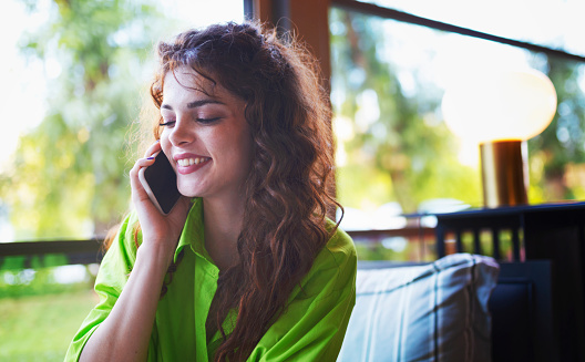 Beautiful woman with curly hair happily making a phone call.