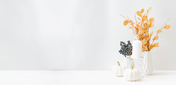 istock Home interior with decor elements. Dry autumn leaves in a vase on a light background 1338499973