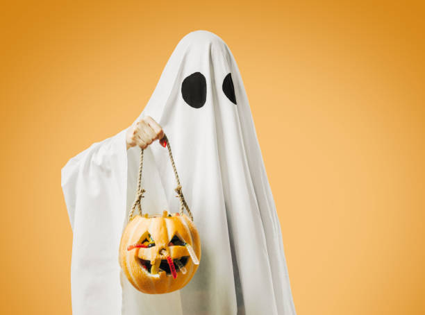 istock Ghost holding jack-o-lantern pumpkin basket with candy in Halloween. 1338501027
