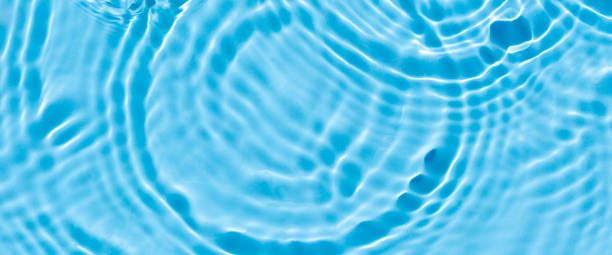 istock Wave from a drop of water on blue water under natural light. Top view, flat lay. 1338502756