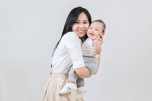 happy family, Young asian mother, hugging her newborn baby smiling, holding him in her arms and smiling from happiness