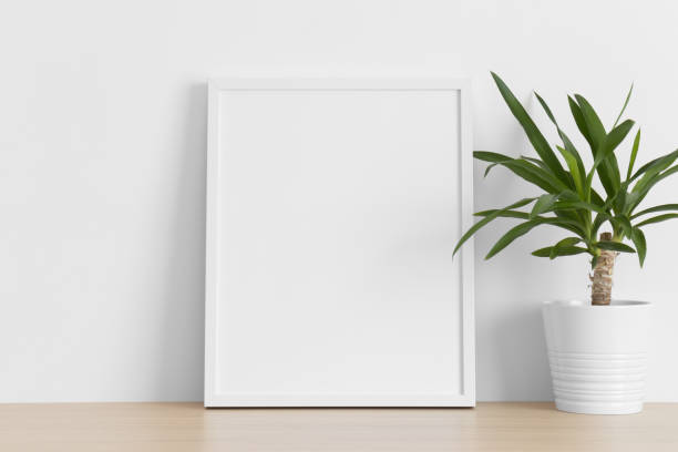 istock White frame mockup with a yucca plant on the wooden table. 1338504046