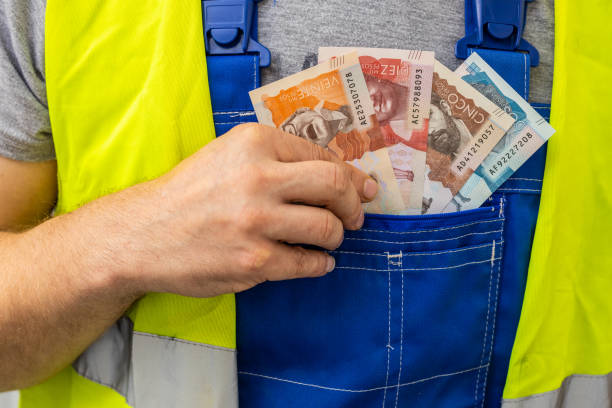 Worker counting his earnings, Colombia money, Concept of wages and labor costs in industry Worker counting his earnings, Colombia money, Concept of wages and labor costs in industry colombian peso stock pictures, royalty-free photos & images