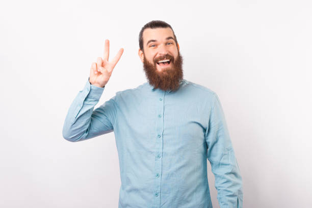 istock Bearded man is showing peace gesture over white background. 1338512739