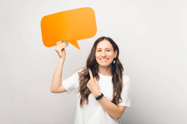 istock Look. Young long haired woman is holding an orange speech bubble. 1338512854