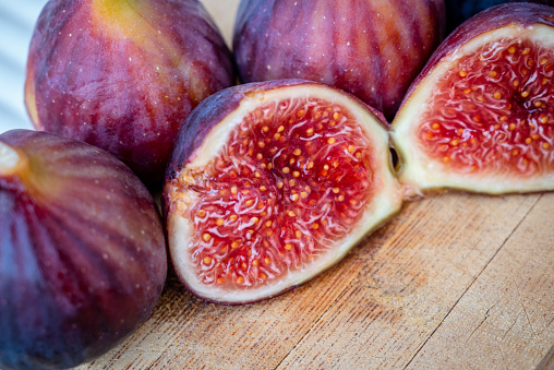 Fresh purple figs cut in halves on wooden cutting board