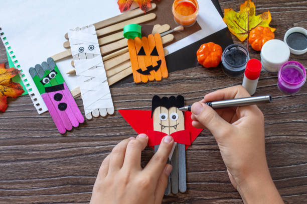 istock Instructions, step 7. Halloween ghost and vampire toy gift stics puppets on wooden table. Handmade. Project of children's creativity, handicrafts, crafts for kids. 1338515529