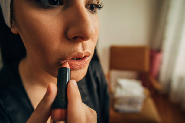 Beauty Model Girl put on Red Lipstick. Makeup Artist painting Lips, one women , lipstick, close up
