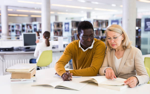 istock Friendly adult students preparing in library 1338516071