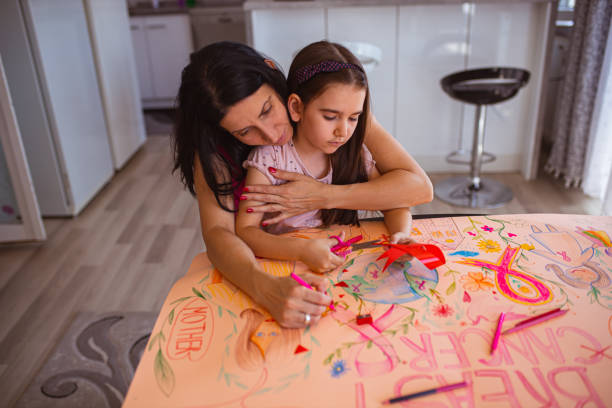 mother teaches her daughter about breast cancer, while both drawing and coloring poster for breast cancer awareness month - community outreach connection child paper imagens e fotografias de stock