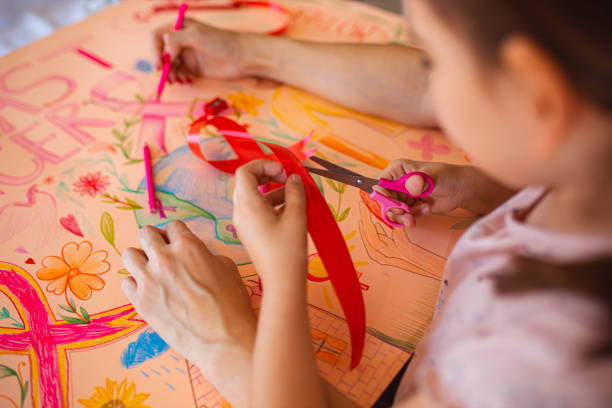 가위를 사용하여 빨간 리본을 자르는 돌보는 소녀, 유방암 인식의 달지원 기구 만들기 - community outreach connection child paper 뉴스 사진 이미지