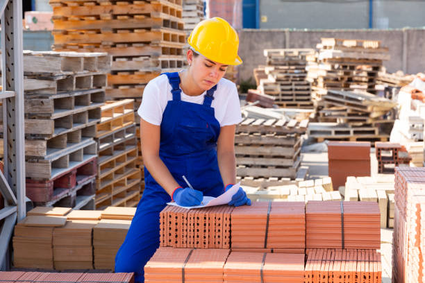istock Young female worker writing beside brick stacks 1338517709